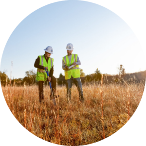 Two people in field with hard hats.